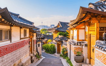 Wisatawan mengenakan hanbok berjalan di Bukchon Hanok Village, Seoul, dengan rumah hanok tradisional dan pemandangan estetik.